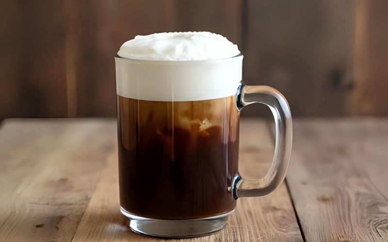 A traditional Irish coffee glass with a distinct dark coffee layer and a thick white cream float.
